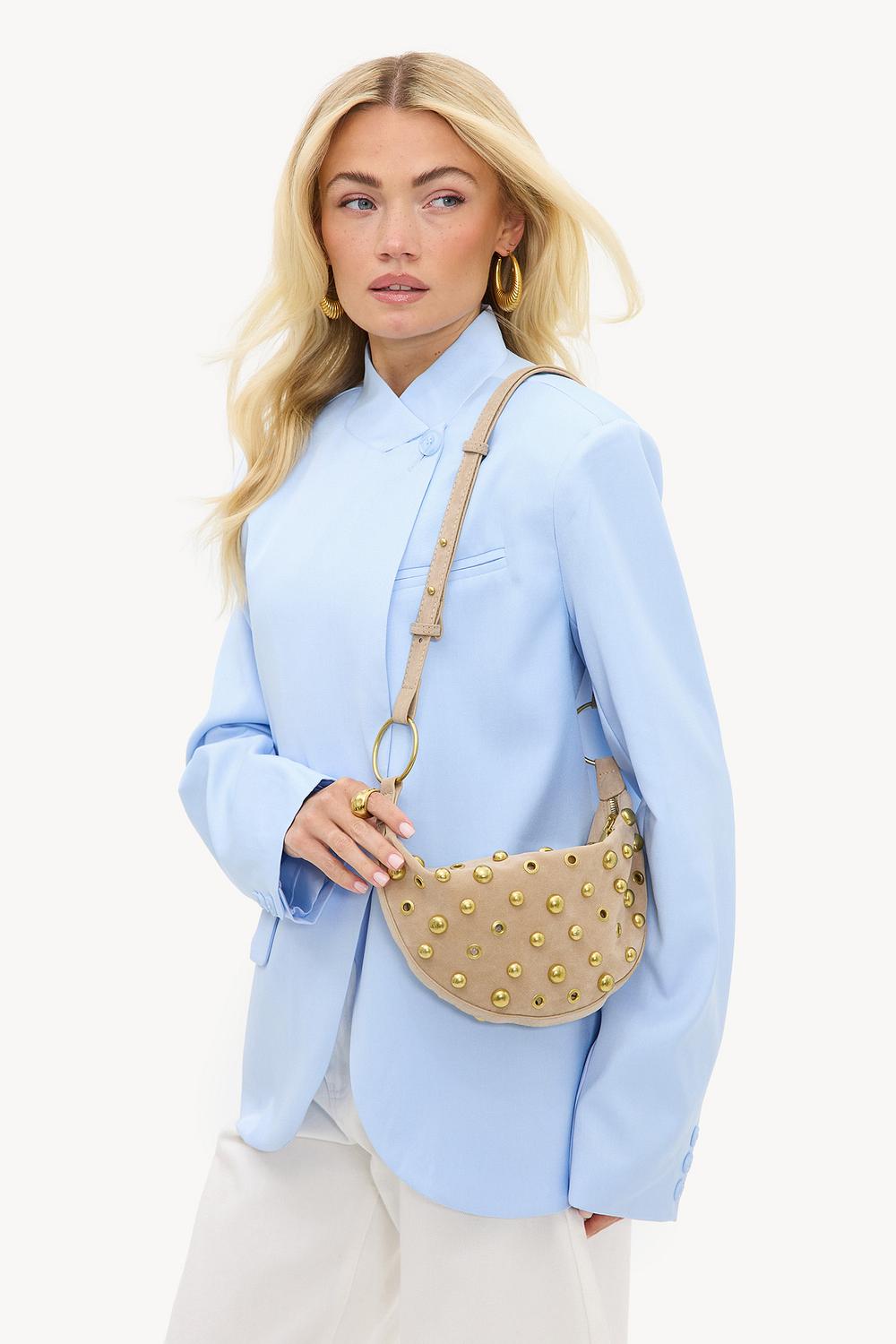 Bolso beige con tachuelas doradas.