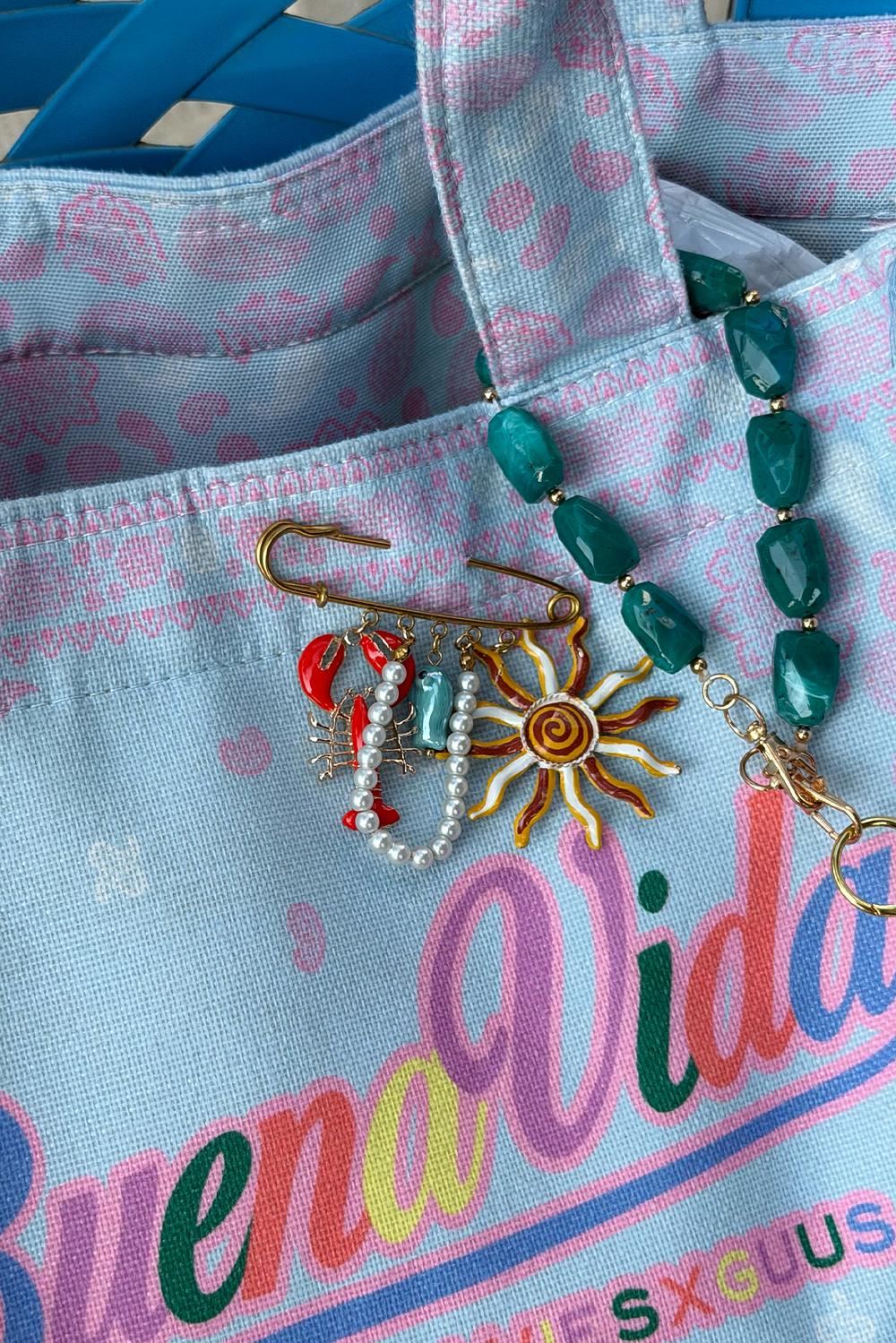 Broche dorado con dijes