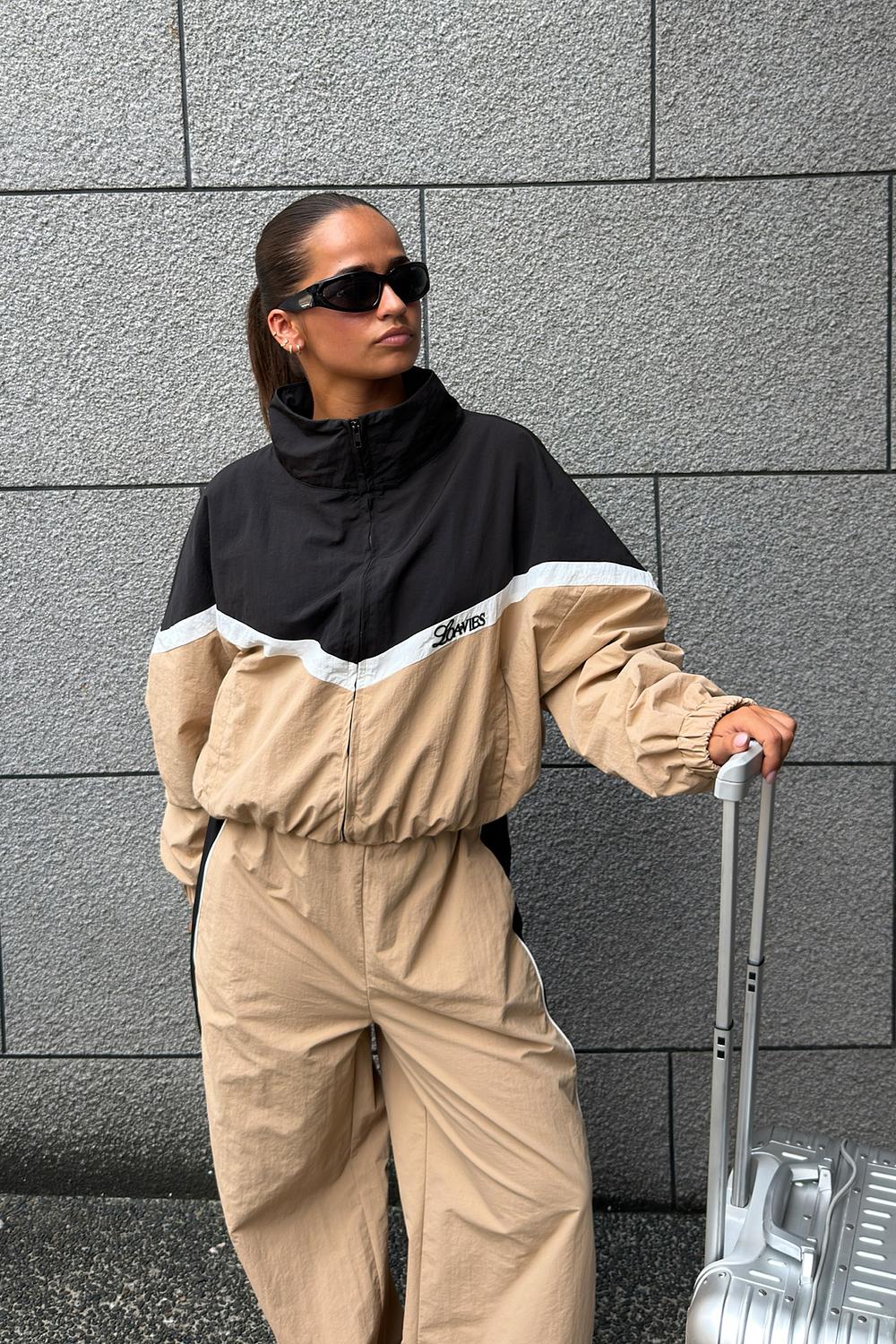 Black jacket with beige and white details and a logo